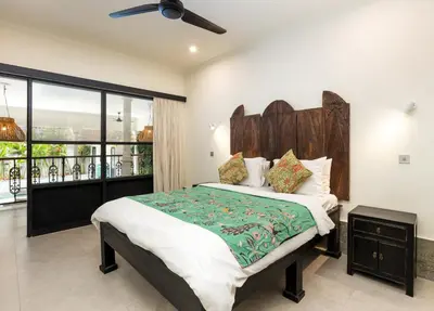 a bedroom with a large bed with a wooden headboard at Villa Baruna Seminyak in Seminyak