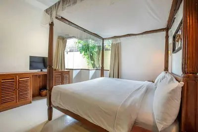 a bedroom with a canopy bed and a television at Clasic Private Pool Villa in Seminyak in Seminyak