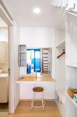 a kitchen with white walls and a counter with a stool at The Blue Loft Seminyak free scooter in Seminyak