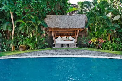 a house with a bed next to a swimming pool at LataLiana Seminyak in Seminyak