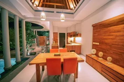 a dining room with a wooden table and orange chairs at The Kasih Villas & Spa in Seminyak