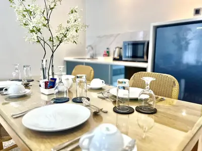 a wooden table with plates and glasses on it at The Bay Sunflower Apartment in Nusa Dua