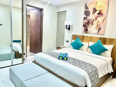 a bedroom with a king sized bed with blue accents at The Bay Sunflower Apartment in Nusa Dua