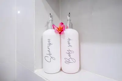 two white bottles with a pink flower on a shelf at TC Villa Taman Mumbul Nusa Dua in Nusa Dua