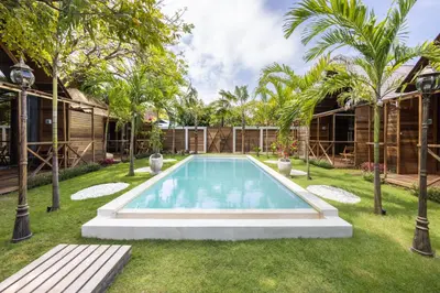 a swimming pool in a yard with palm trees at Bali Cozy Bungalows, Nusa Dua Benoa in Nusa Dua