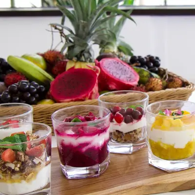 a table with four glasses of desserts and a basket of fruit at Two-Bedroom Pool Villa at Anwa Residences in Canggu