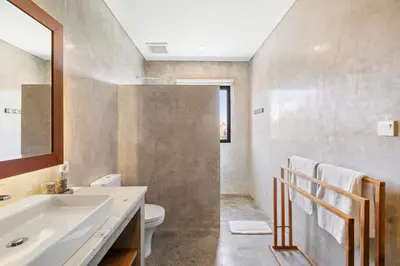 a bathroom with a sink and a toilet and a mirror at Abu Villa by Betterplace in Canggu