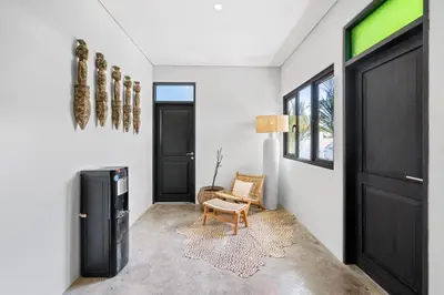 a living room with a black door and a chair at Abu Villa by Betterplace in Canggu