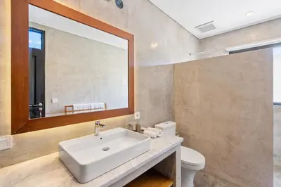a bathroom with a sink and a mirror and a toilet at Abu Villa by Betterplace in Canggu