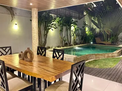 a dining room with a table and a swimming pool at Mila's Villa in Legian