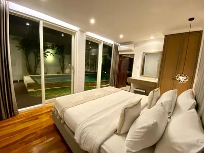 a large bed with white pillows in a room with windows at Mila's Villa in Legian