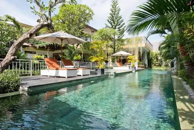 a swimming pool with two chairs and an umbrella at Zolina Villa 4 Bedrooms in Kerobokan