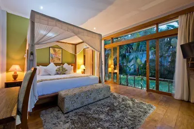 a bedroom with a canopy bed and a large window at Zolina Villa 4 Bedrooms in Kerobokan
