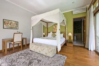 a bedroom with a canopy bed and a table and chair at Zolina Villa 4 Bedrooms in Kerobokan