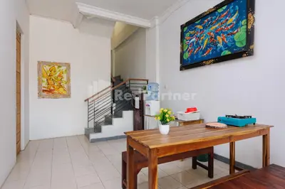 a living room with a table and a painting on the wall at Shooting Star Hostel Kuta RedPartner - mixed dormitory in Legian