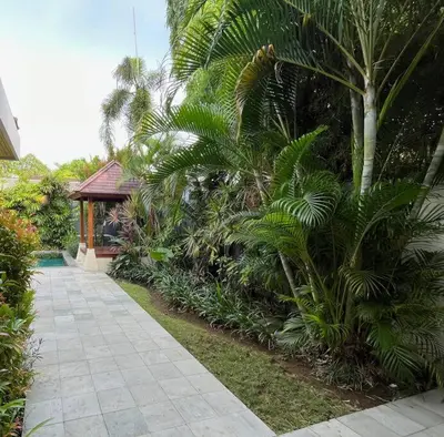 a garden with palm trees and a walk way at Villa Plawa in Seminyak