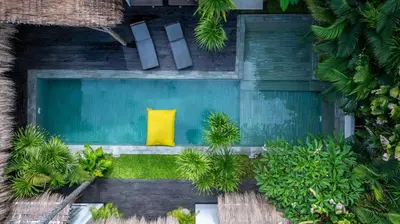 a yellow pillow sits on a bench in a garden at Villa Micasa - Tropical Oasis 4BR Villa with Private Pool, Perfect for Big Groups, 12 Minutes to the Beach in Kerobokan