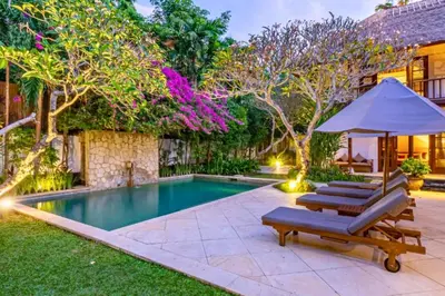 a pool with two lounge chairs and an umbrella at Magnificent 4 BR Private Pool Villa NE10 in Jimbaran
