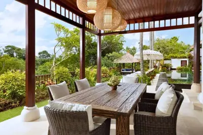 an outdoor dining room with a wooden table and chairs at Mandevilla 4 BR Private Pool Villa NE25 in Jimbaran