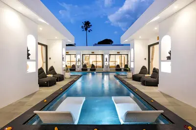 a swimming pool in a house with couches and chairs at Villa Kelolyne in Seminyak