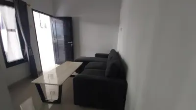 a living room with a black couch and a table at Chandra's guest house in Pesanggaran