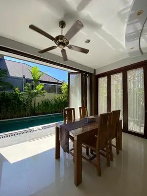 a dining room with a table and chairs and a ceiling fan at Villa Granatlia in Sanur