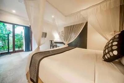 a bedroom with a large white bed with curtains at Villa Kuda Sumba Umalas - Seminyak Area in Kerobokan