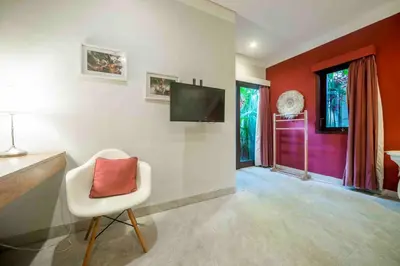 a living room with a white chair with a red pillow at Villa Kuda Sumba Umalas - Seminyak Area in Kerobokan