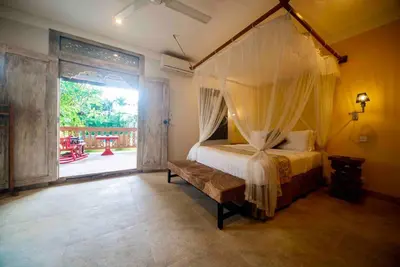a bedroom with a canopy bed and an open door at Villa Kuda Sumba Umalas - Seminyak Area in Kerobokan