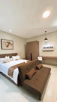 a bedroom with a large bed and a couch at Nawasena Room Suite in Sanur