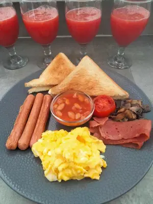 a blue plate of breakfast food with eggs sausage and tomatoes at Villa Dekat Pantai Batu Belig in Canggu