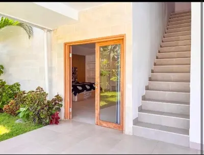 a glass door to a house with a staircase at Villa Dekat Pantai Batu Belig in Canggu