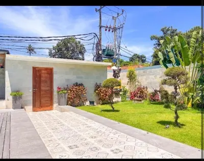 a small white house with a door and a yard at Villa Dekat Pantai Batu Belig in Canggu