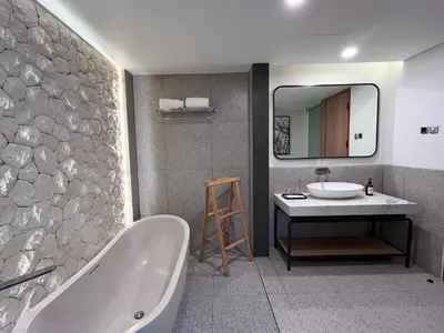 a bathroom with a tub and a sink and a mirror at Luminor Hotel Legian Seminyak - Bali in Legian