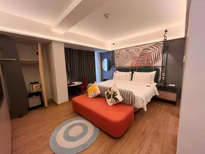 a bedroom with a bed and a red couch at Luminor Hotel Legian Seminyak - Bali in Legian