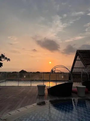 a pool with a hot tub on a deck with the sunset at Luminor Hotel Legian Seminyak - Bali in Legian