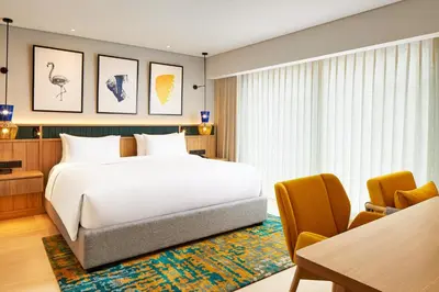 a bedroom with a large white bed and a table at voco Bali Seminyak by IHG in Seminyak