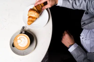 a table with a cup of coffee and a croissant at voco Bali Seminyak by IHG in Seminyak