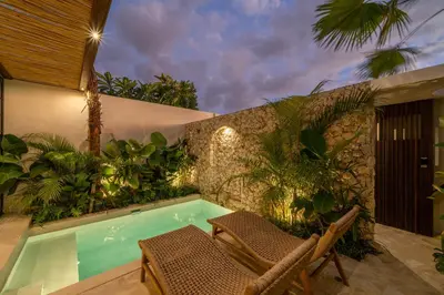 a swimming pool in a garden with two chairs at Casa Melosa 2 : Charming and Intimate 1BR Villa Nestled in Umalas in Canggu