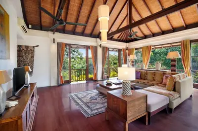 a living room with a couch and a tv at Barimantra 4BR Trees View Pool Villa CYN in Jimbaran
