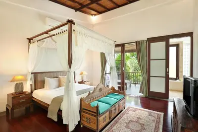 a bedroom with a canopy bed and a balcony at Sujiwana 2BR Luxury Jungle Pool View Villa CYN in Jimbaran