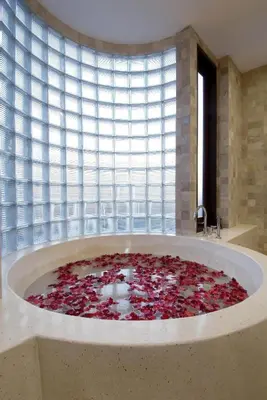 a large tub filled with red flowers in front of a window at Sujiwana 2BR Luxury Jungle Pool View Villa CYN in Jimbaran