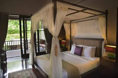 a bedroom with a canopy bed and a balcony at Sujiwana 2BR Luxury Jungle Pool View Villa CYN in Jimbaran