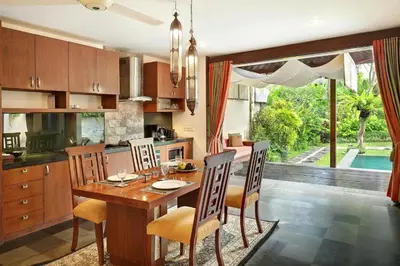 a kitchen with a wooden table and chairs and a dining room at Sujiwana 2BR Luxury Jungle Pool View Villa CYN in Jimbaran