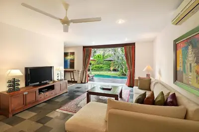 a living room with a couch and a tv at Sujiwana 2BR Luxury Jungle Pool View Villa CYN in Jimbaran