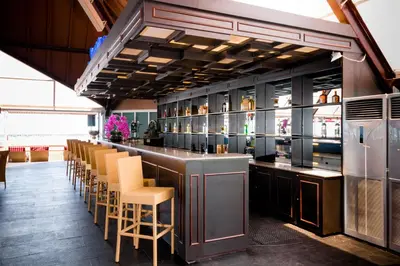 a bar in a restaurant with yellow chairs at Kutabex Beachfront Hotel in Kuta