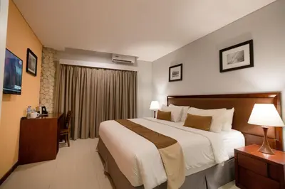 a hotel room with a large bed and a desk at Kutabex Beachfront Hotel in Kuta