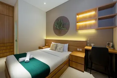 a bedroom with a bed and a desk and a chair at Cove Tripuri House Bali in Denpasar