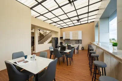 a dining room with tables and chairs and a kitchen at Cove Tripuri House Bali in Denpasar