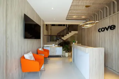 an office lobby with orange chairs and a staircase at Cove Tripuri House Bali in Denpasar